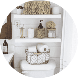Clever Storage Solutions bathroom with white shelves above toilet with black basket full of toilet paper