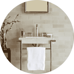 Subway Tile walls in bathroom with small gold sink with small towel rack in front of sink
