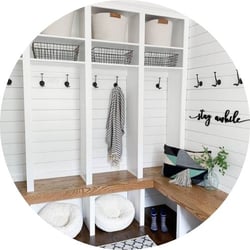modern farmhouse entryway with white walls and black hooks spaced on each wall with brown wood bench 