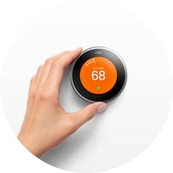 orange nest thermostat with hand setting the thermostat to 68